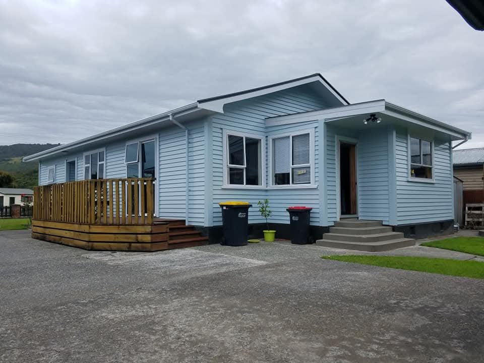 Freshly painted light blue weatherboard house with white trim and a new deck